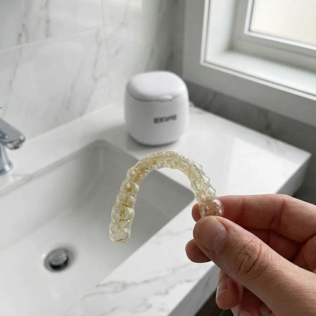 Retainer with yellow buildup and plaque before ultrasonic cleaning